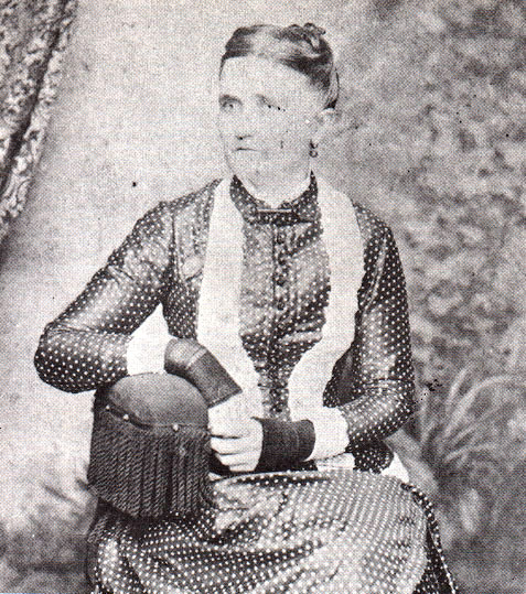 Faded photo of white woman wearing dark dress with small polkadot pattern