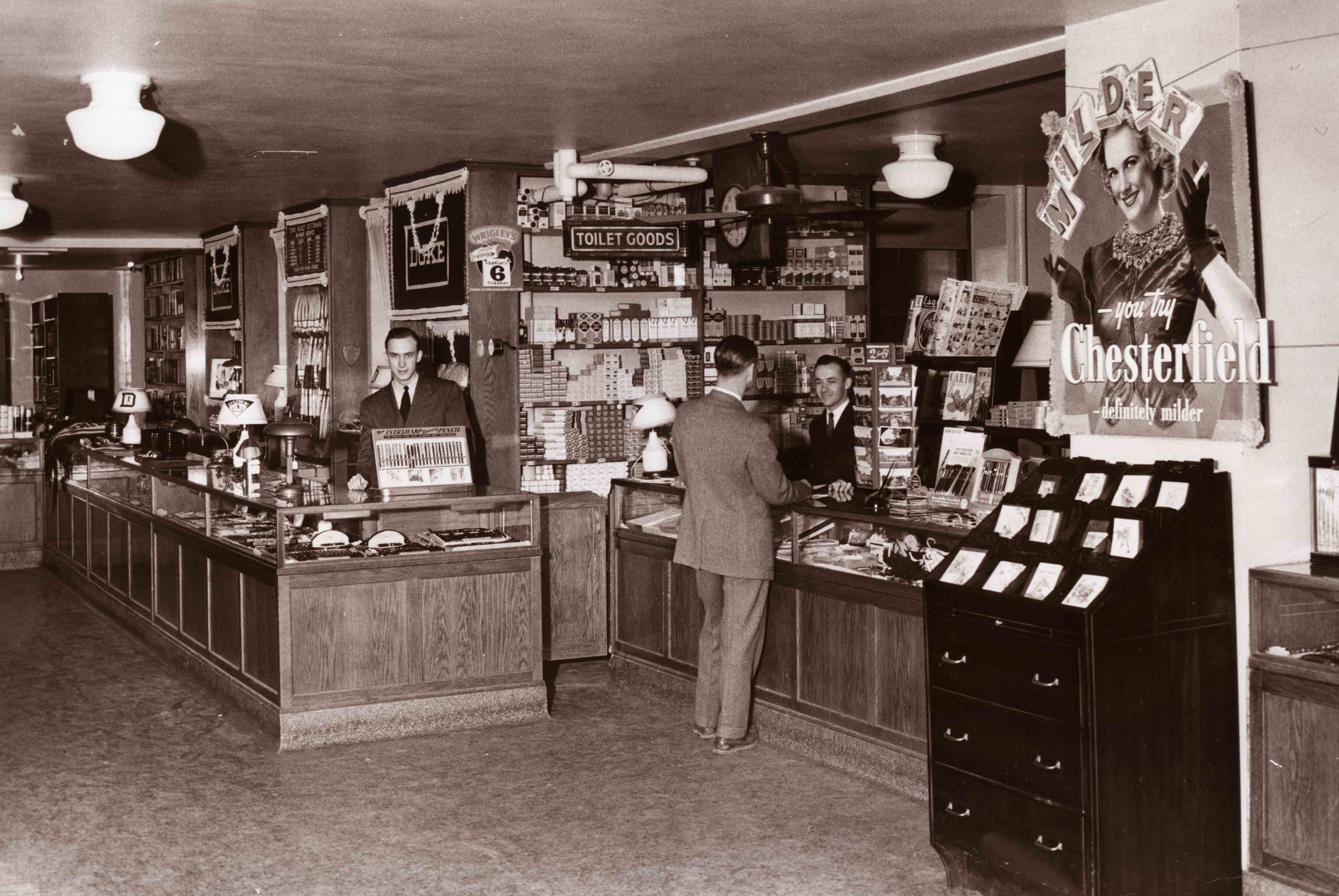 shop counter with 3 people and displays of cigarettes