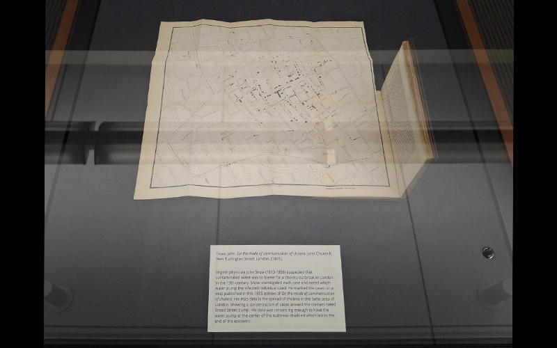 An exhibit case displaying a book with a foldout map and an accompanying exhibit label.