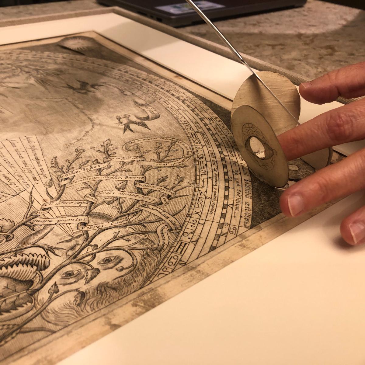 staff member handling delicate foldout on a collection item