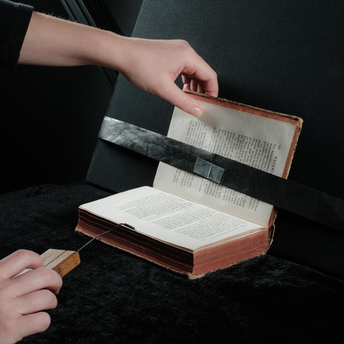 staff member handling a book in a cradle
