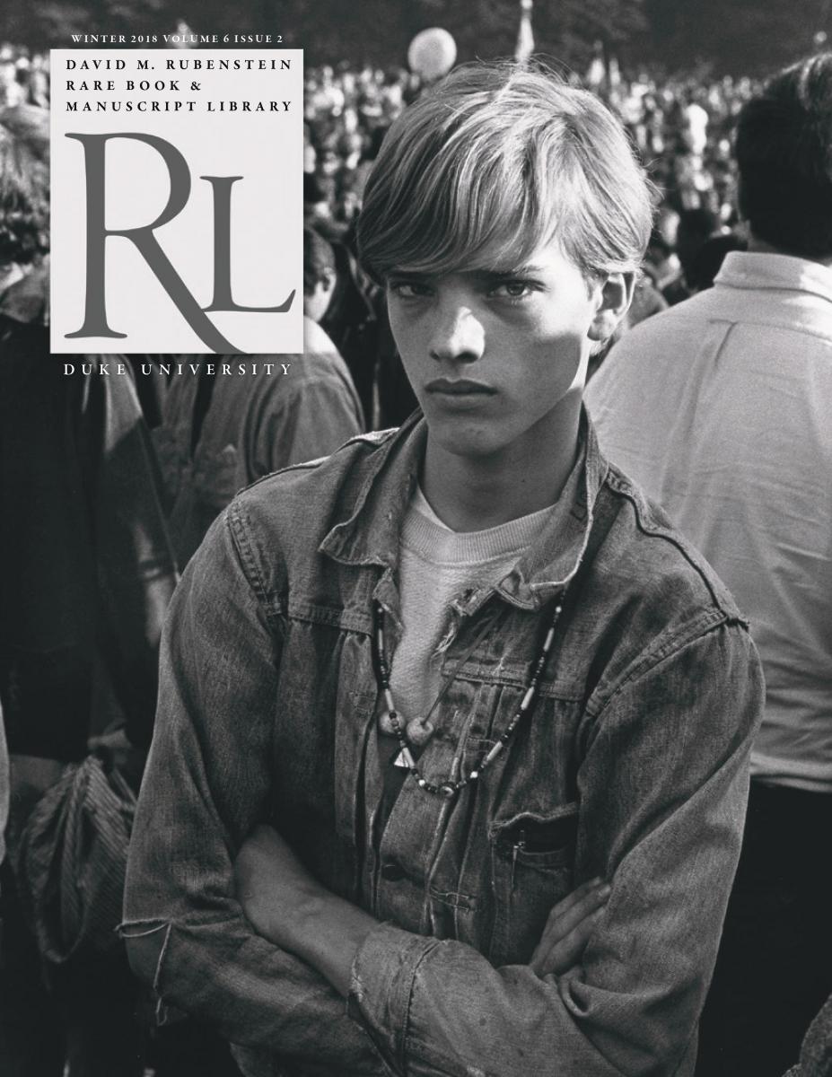 Winter 2018 cover with a black and white photograph of a young white man. He is wearing a denim jacket and necklaces and staring at the camera. He is standing in a crowd of people outside but his back is turned on the people standing in front of him. 